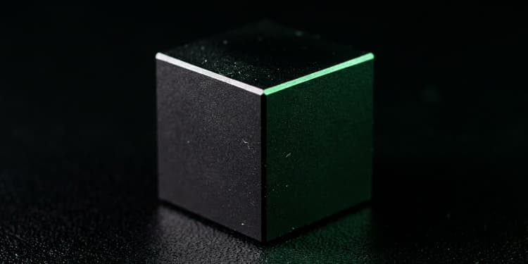 A sealed matte black cube with a single hairline seam glowing green, its contents not visible