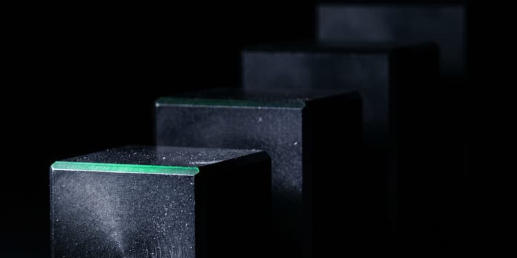 A row of dark stone-textured blocks recedes into blackness, each with a glowing green line along its top front edge.