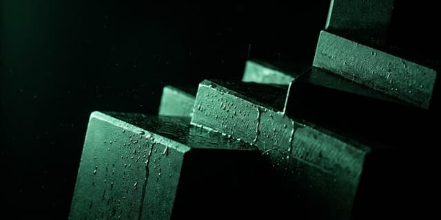 Overlapping angular black planes layered like shingles, raked by hard green light, beaded with water