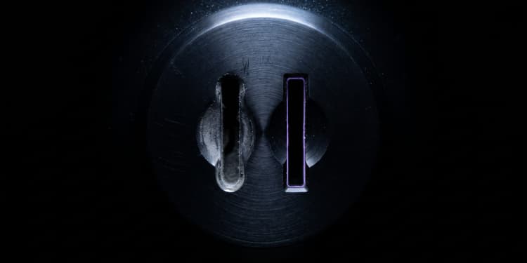 Close-up of a dark metal plate with two vertical slots, one plain and one outlined in glowing purple light.