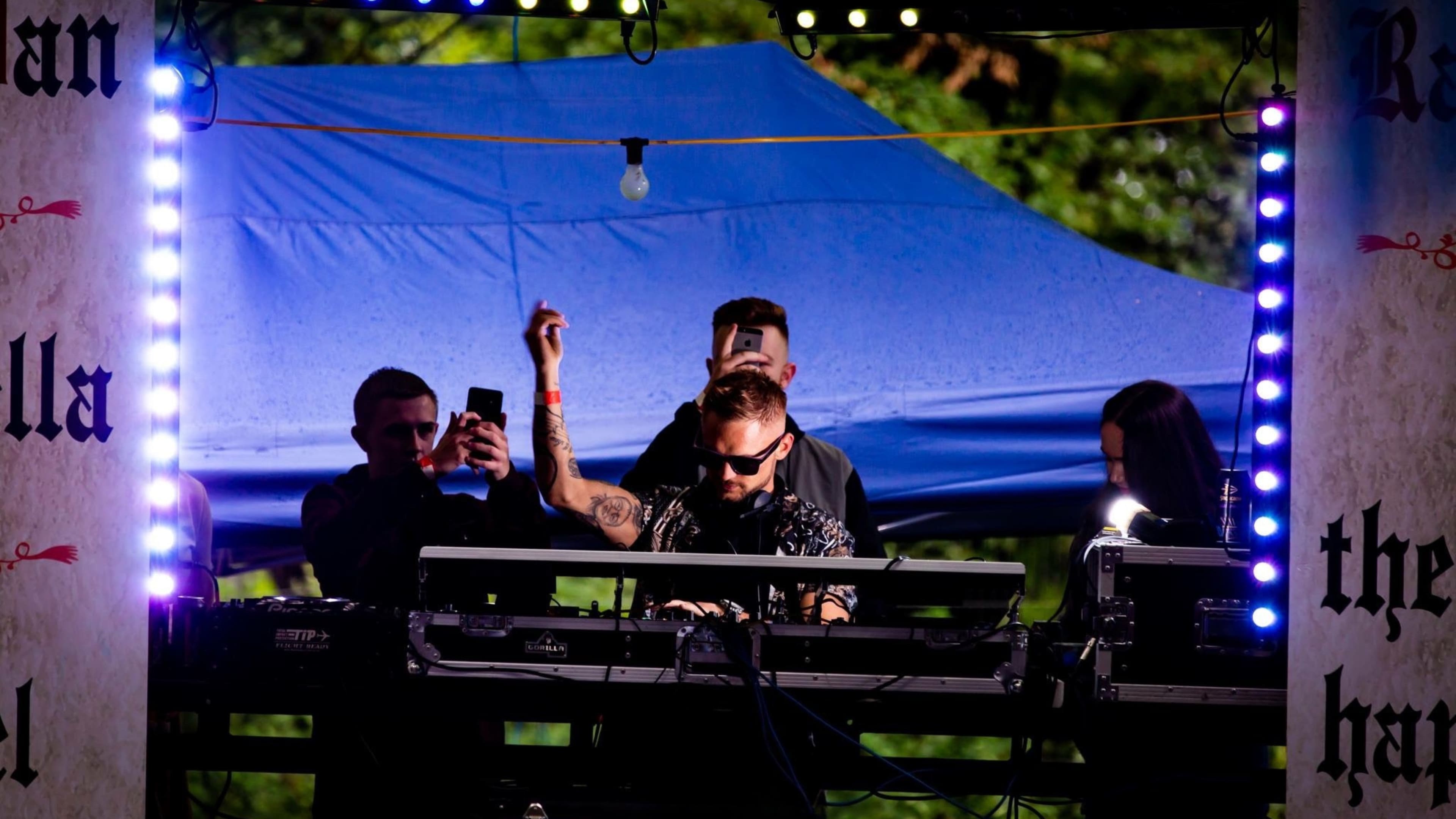 Chris Sarchet Bell DJing an outdoor evening set under festival lighting, 2014