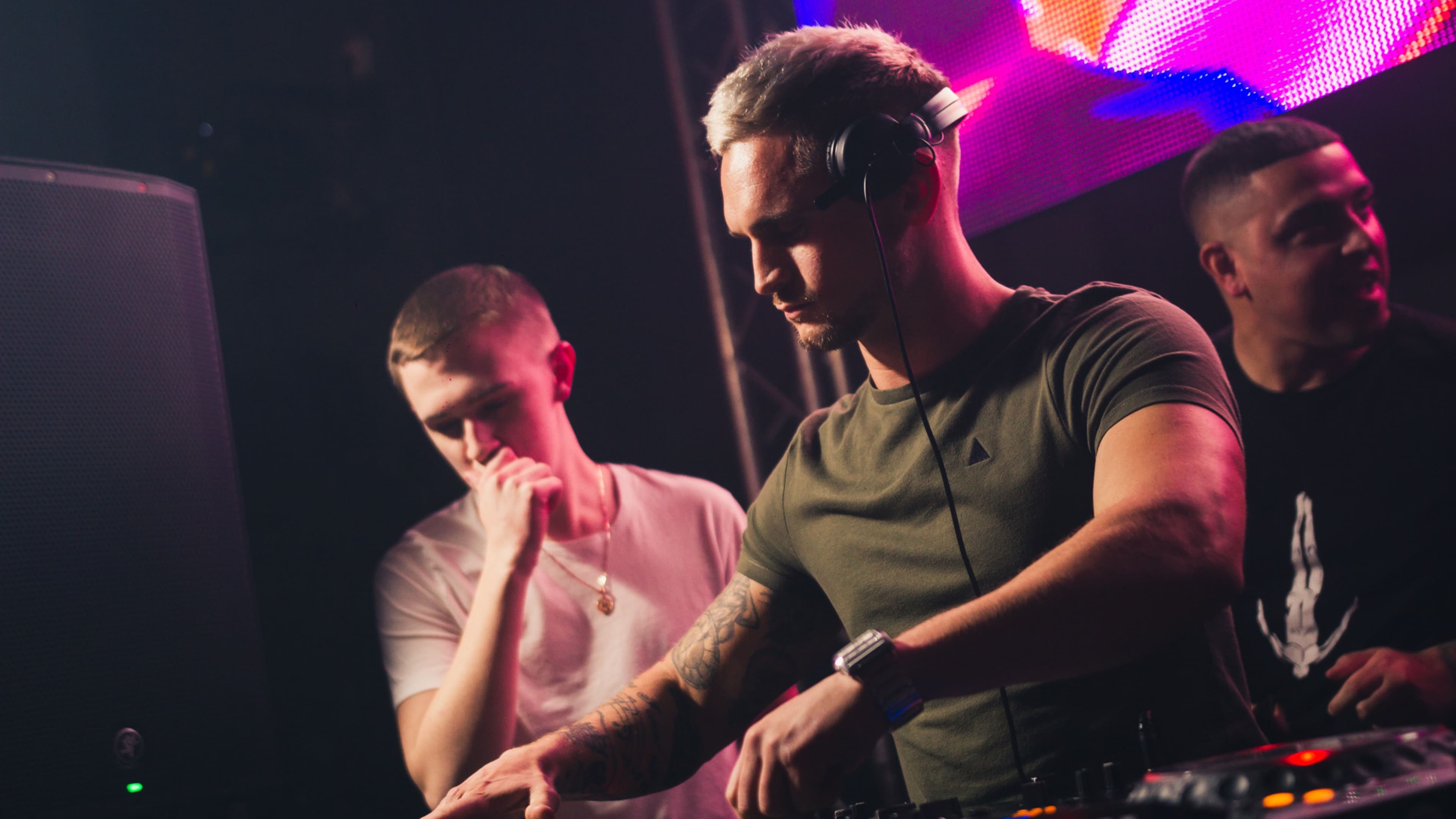 Chris Sarchet Bell on stage with two other DJs during a live set, 2014