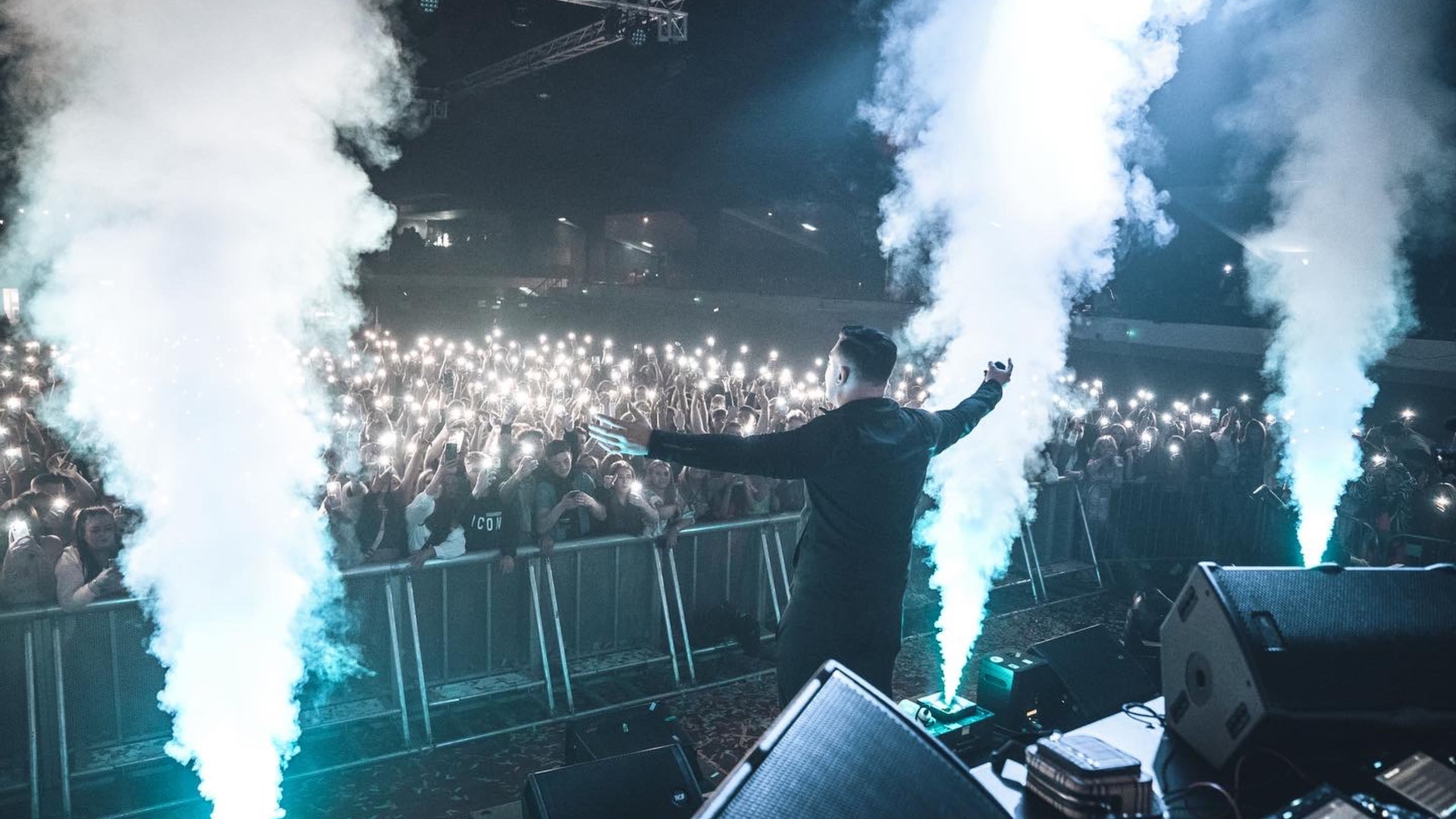 DJ performing on stage with smoke cannons at a Shutdown show, 2016