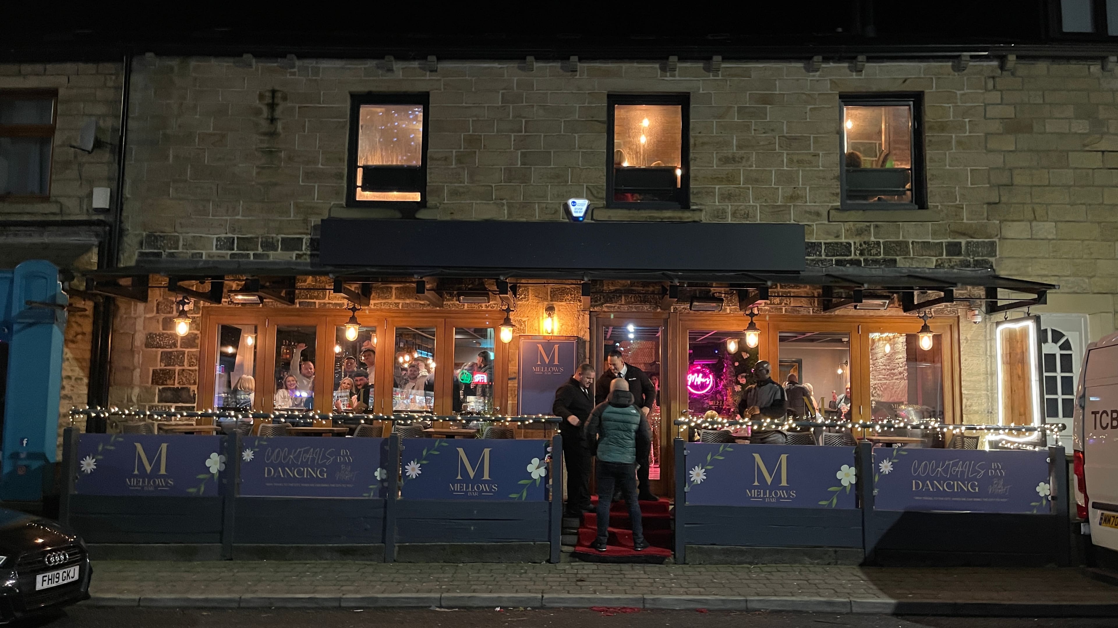 Exterior of the refurbished bar lit up in the evening, 2023